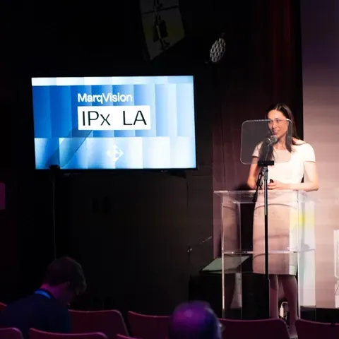 A keynote speaker at the podium under the IPx LA screen